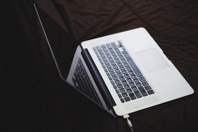 an open laptop computer sitting on top of a bed