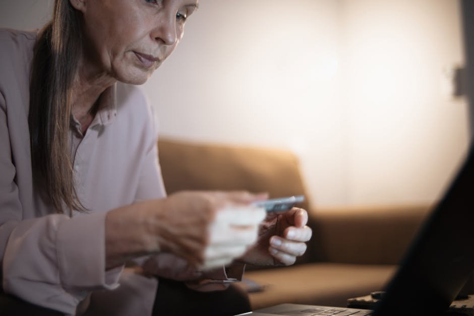 Senior woman using a laptop and credit card for online shopping in cozy home setting.