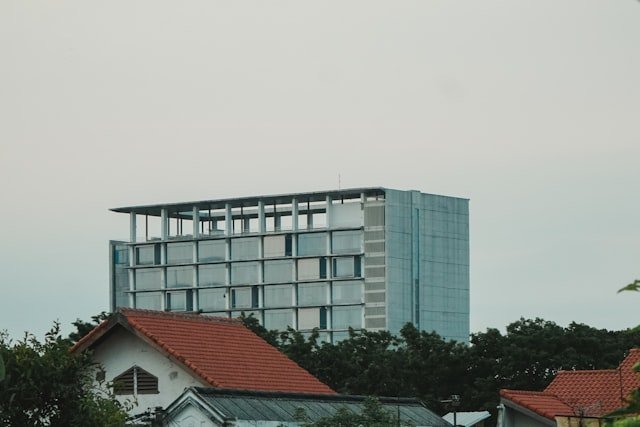 a tall building with a red roof next to trees