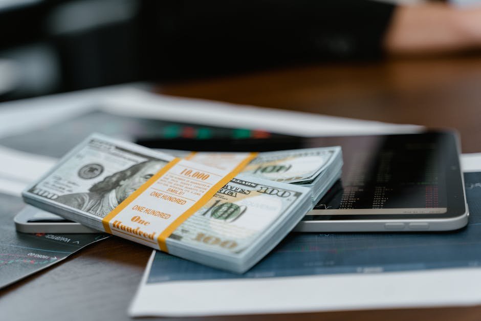A stack of 0 bills placed on a tablet displaying financial graphs, representing modern finance.
