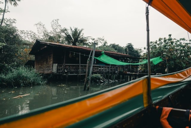 A boat ride passes a waterside house.