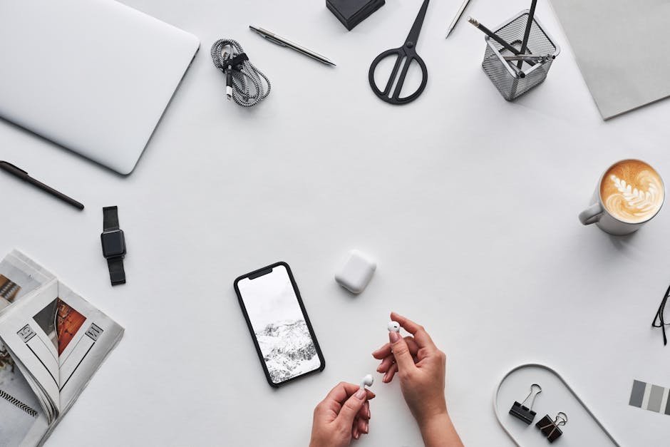 Flat lay of a modern workspace featuring tech devices, a latte, and office supplies.