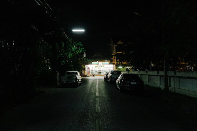 a street at night with cars parked on the side of the road