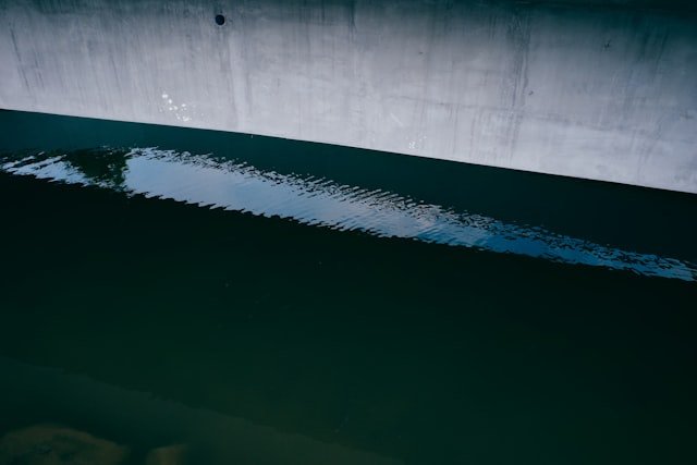 Water reflects a concrete structure.