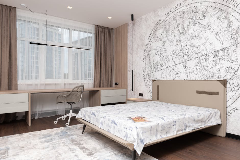 Modern room with wide bed under map on wall and long table with comfortable chair