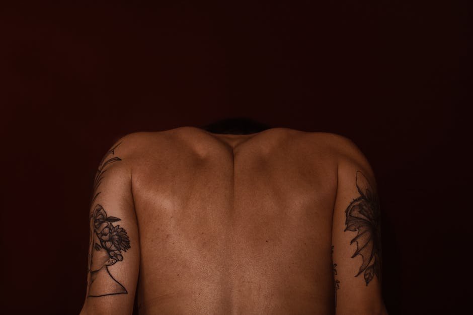 Artistic depiction of a tattooed man's back against a dark background.