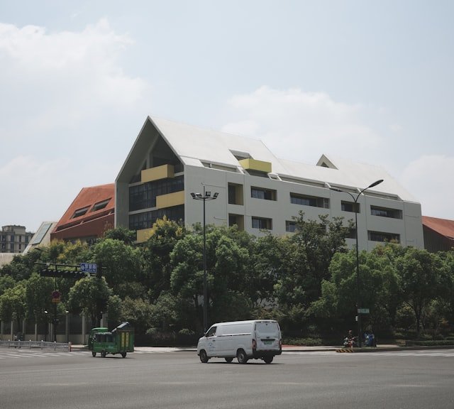 a white van driving down a street next to a tall building